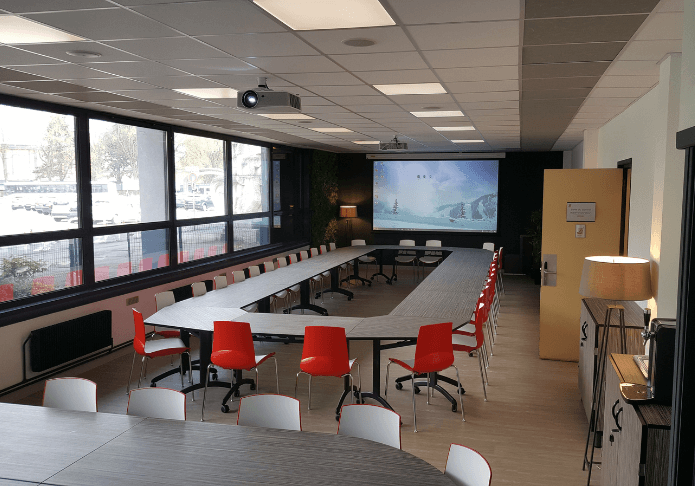 salle de réunion équipée avec mobilier professionnel, chaises colorées et vidéoprojecteur pour collectivités ou entreprises
